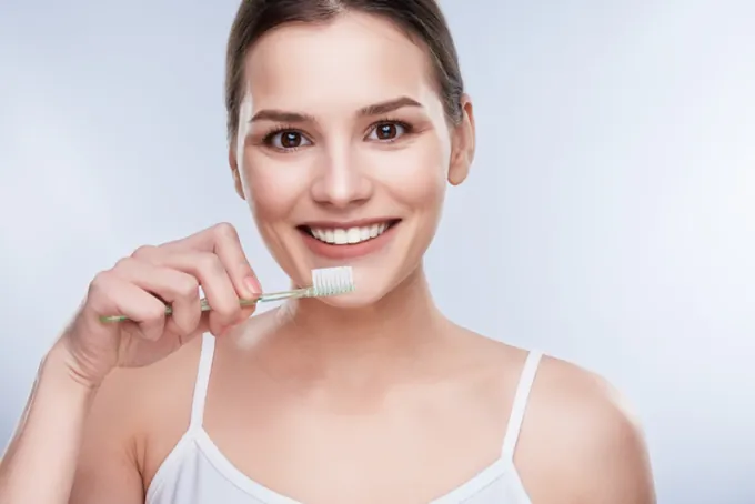 Mulher sorrindo com a escova de dentes na mão