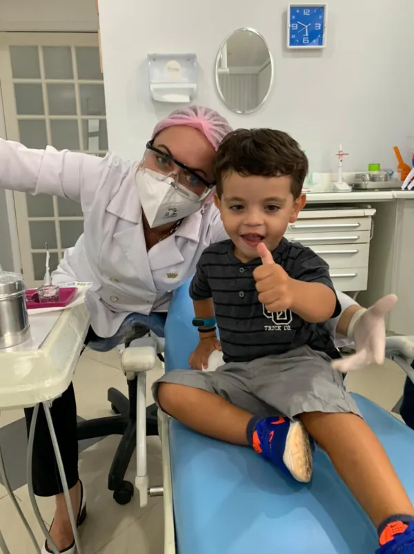 Criança faz sinal de positivo na cadeira do dentista